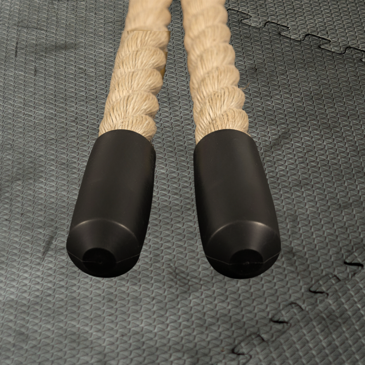 Pair of battle rope handles with black grips on a textured gray gym surface