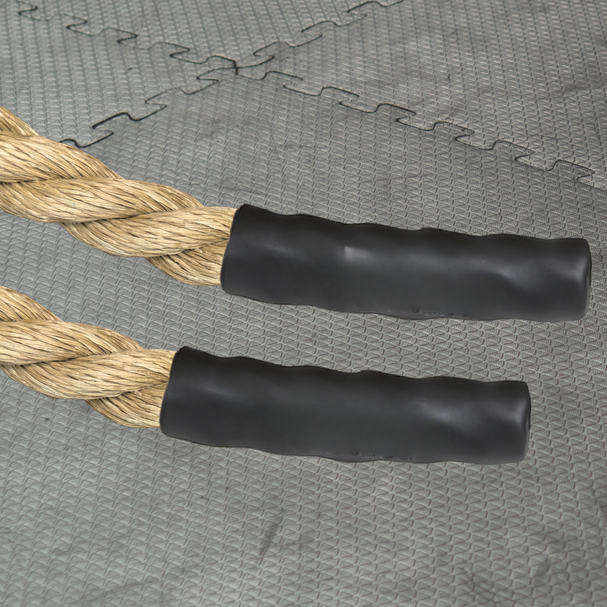 Pair of battle rope handles with black grips on a textured gray gym surface
